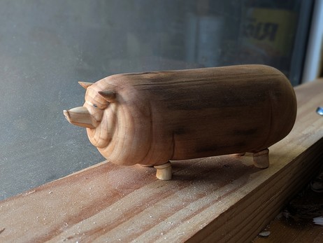Woodcarved chunky hog on a workbench.