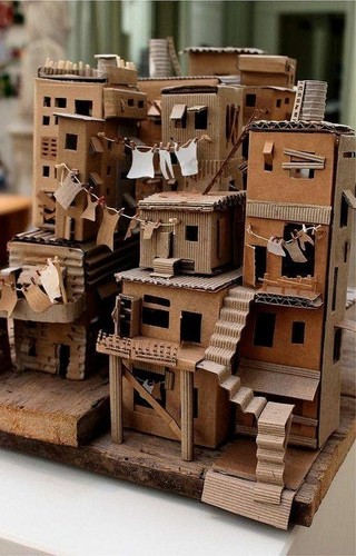 A small model of residential buildings made of cardboard. There are stairs also made of cardboard and laundry made of paper hanging across the front of the buildings
